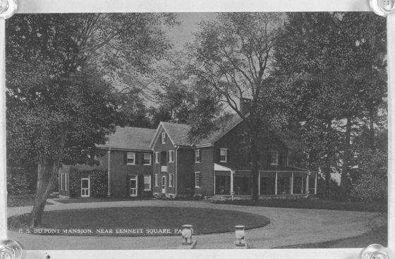 Black and white photo of historic brick house with a roundabout road leading up to it