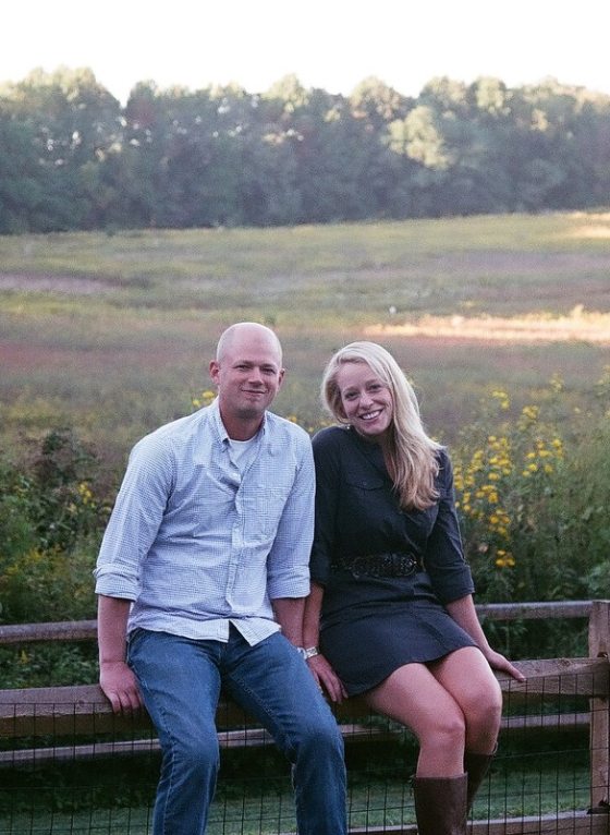 two people sitting on a bench in a meadow