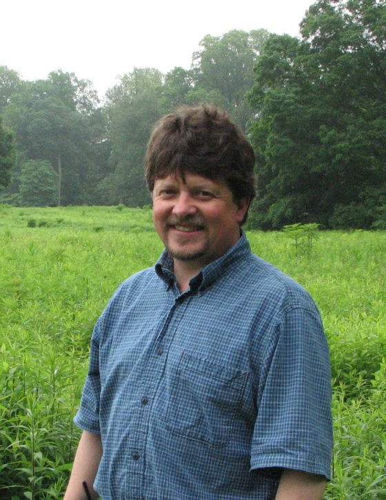 a person smiling with bright green grass in the background 