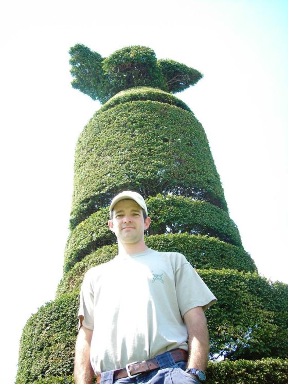 gardener standing in front of a tall topiary form