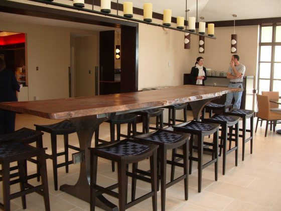 long carved and polished wood dining table with wooden barstools all around