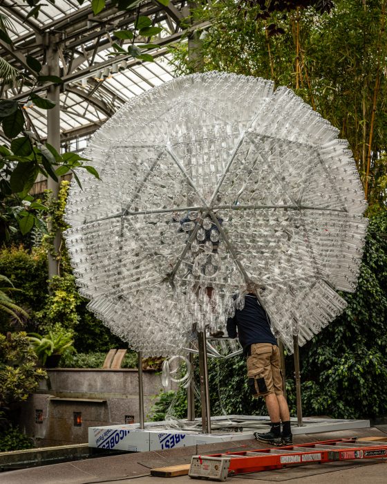 people assembled acrylic panels to a metal dome to complete a sphere