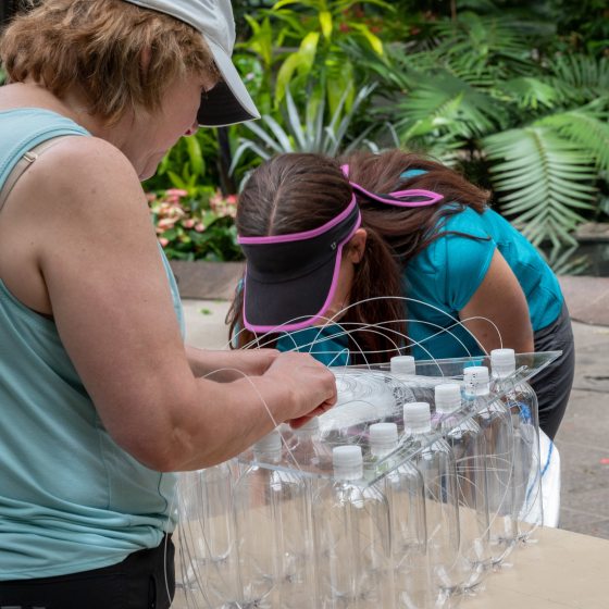 people putting fiber optic cable and threaded each fiber through the holes in the bottle caps