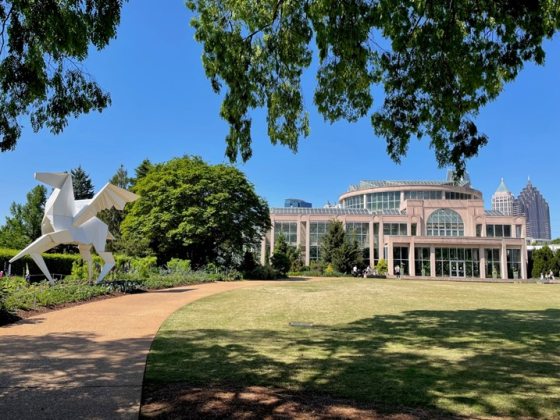 sculpture of a white pegasus on the left with an tan and glass building on the right