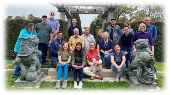 groupd of 18 people sitting between two gryphon sculptures