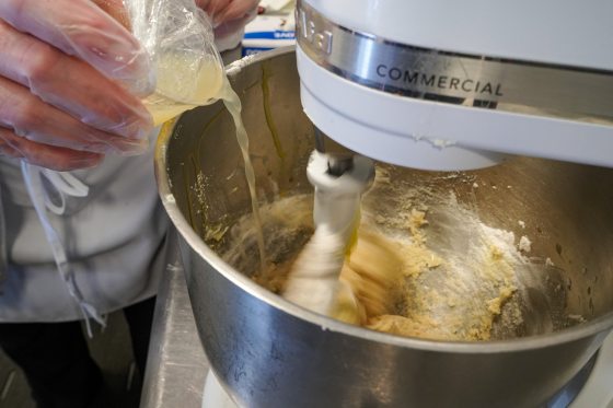close up image of a automatic mixer and someone pouring in ingredients