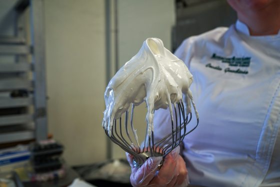 person holding a whisk with meringue on it