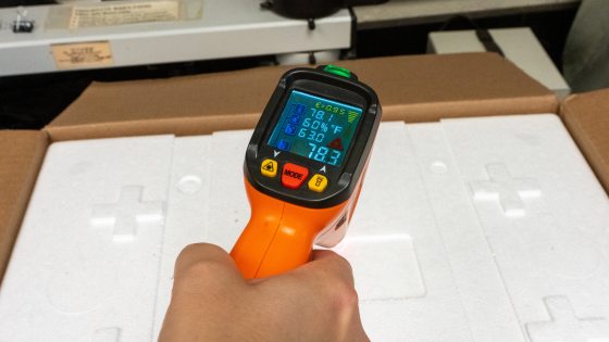 a person taking the temperature of a box of insects using an organge thermometer