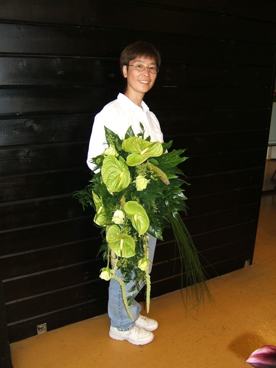 a person holding a bouquet of large green leaves and palm fronds