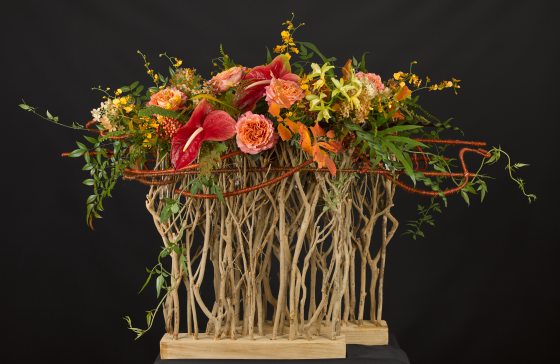modern tropical floral arrangement with red and orange flowers atop twigs and sticks 