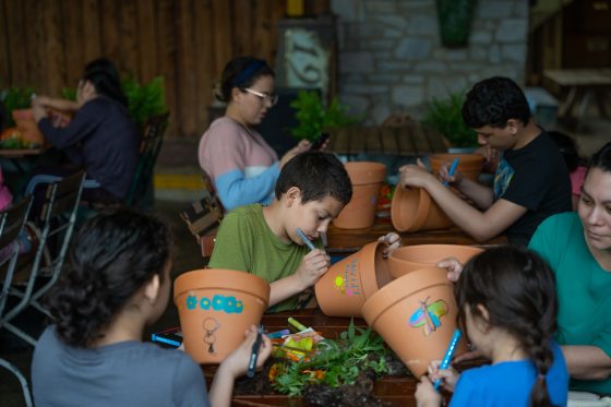 a group of kids painting terra cotta pots with markers