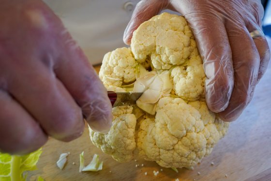 a person slicing cauliflower with a knife