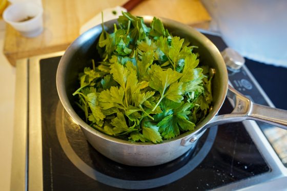 a saucepan on the stove filled with parsley