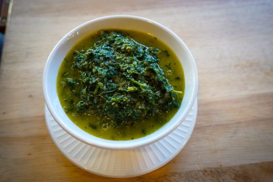 a white bowl filled with a green herb salsa