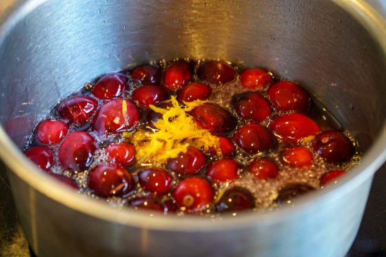 a pot of cranberries and lemon zest boiling