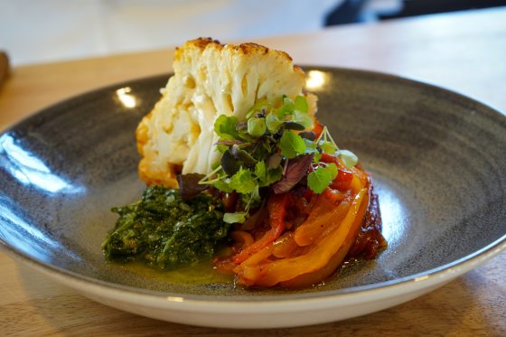 a plate of sliced peppers, cauliflower, and herb salsa