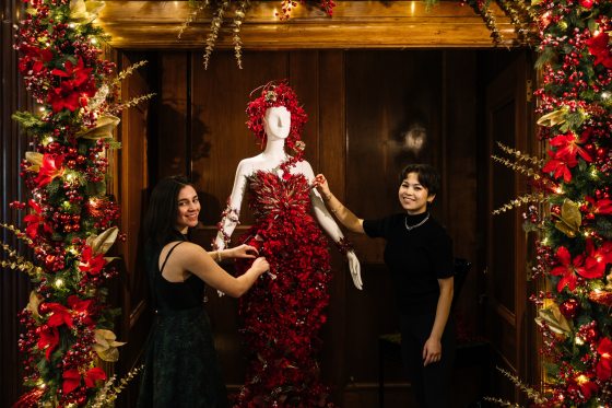 two people adjusting a red dress made of floral material