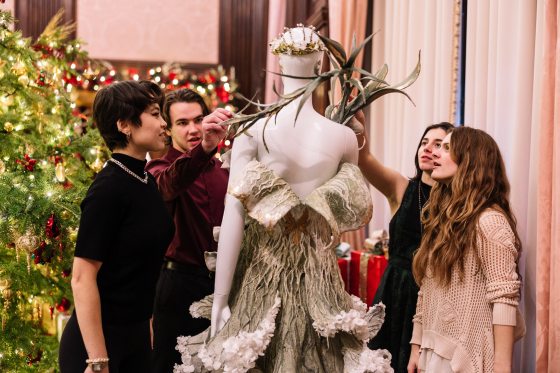 four people standing around a mannequin in green dress made of floral material