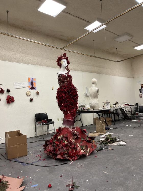 a studio space with a mannequin in a red dress made of flowers
