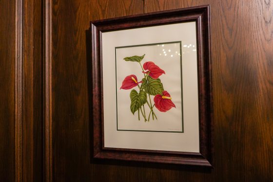 a botanical print in a brown frame of red and green leaves