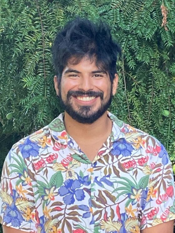 portrait of broadly smiling person with black hair and colorful floral print shirt