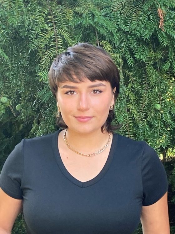 portrait of smiling person with short brown hair and black V-neck top