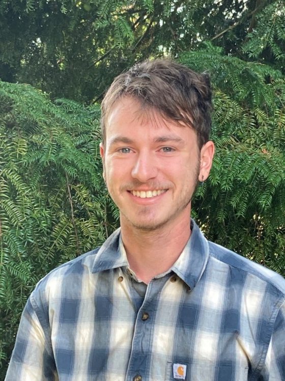 pportrait of smiling person with short brown hair and blue and white plaid shirt