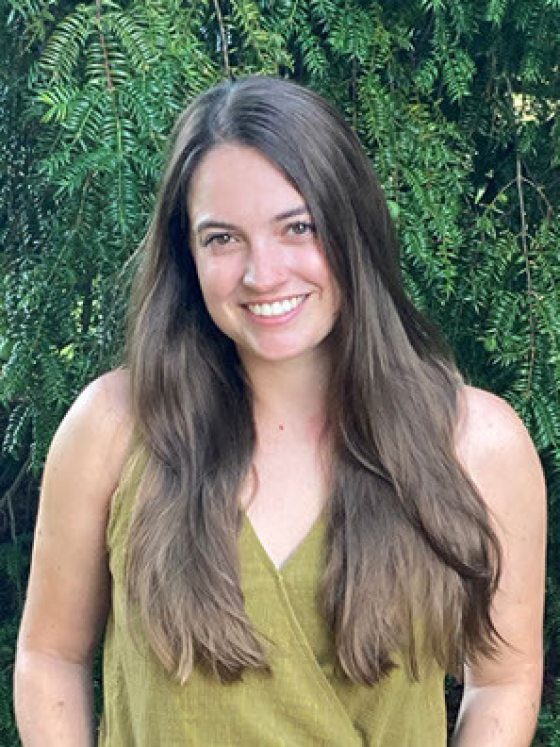 portrait of smiling person with long brown hair and lime-green V-neck tank top