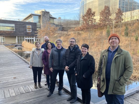 seven people standing outside in a winter landscape smiling at the camera