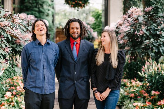 three people next to each other surrounded by blooming flowers