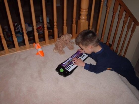 a child laying on the stairs playing a small keyboard