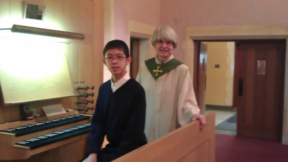 two people standing next to an organ smiling at the camera