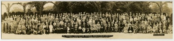 wide shot of a large group portrait seated and standing in front of an outdoor arbor
