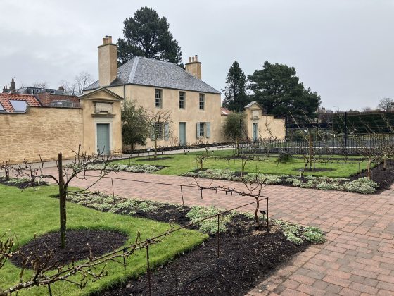 A stucco house set behind garden beds in Scotland. 