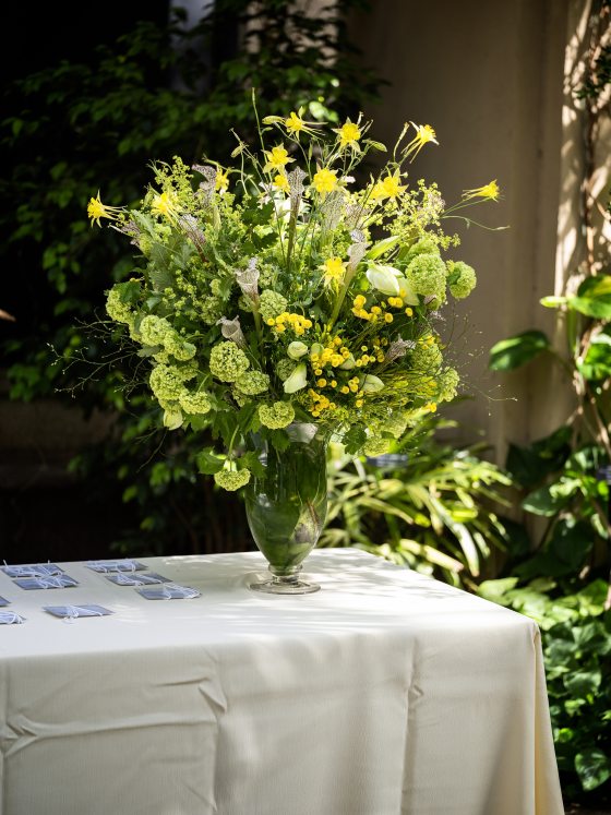 A clear glass vase filled with green and yellow flowers. 