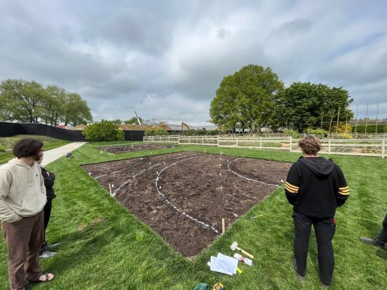 Three people looking at a patch of dirt mapping out a flower bed.