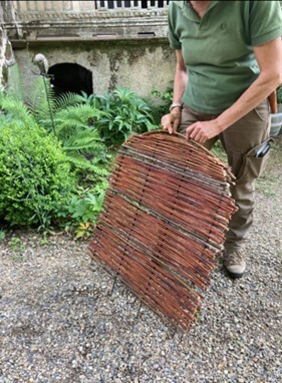 A person holding a weaving made out of willow. 