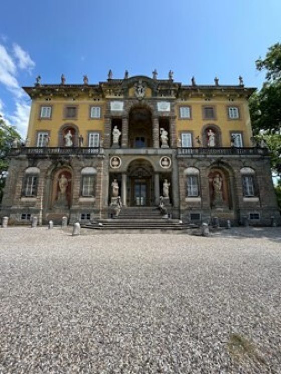 A historic house in Italy with a yellow and stone facade. 