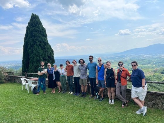 A group of people standing against a stone wall for a group photo. 