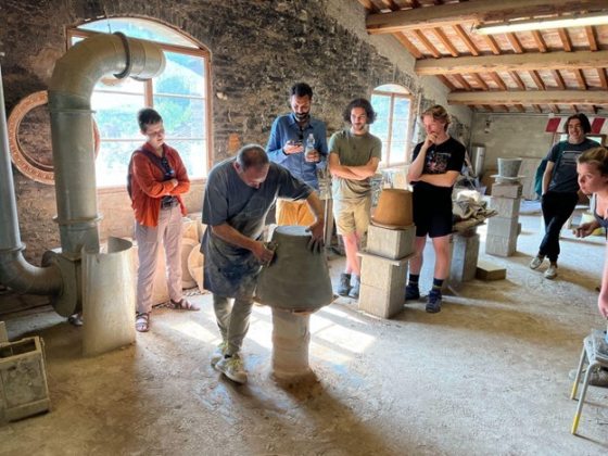 Students in a stone building watching a handsculpting demo.