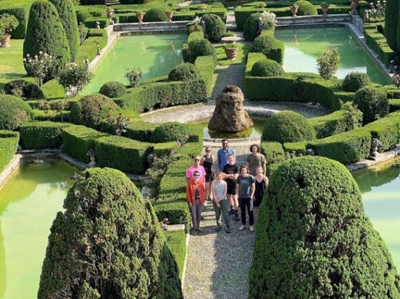 A group of students standing inside a topiary and fountain garden in Italy.