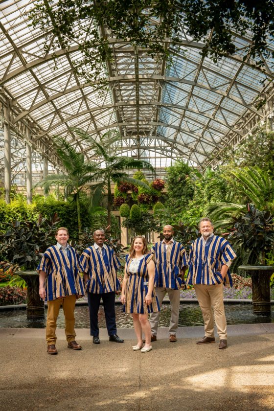Five people in a conservatory posing for a picture in traditional Ghanaian outfits.