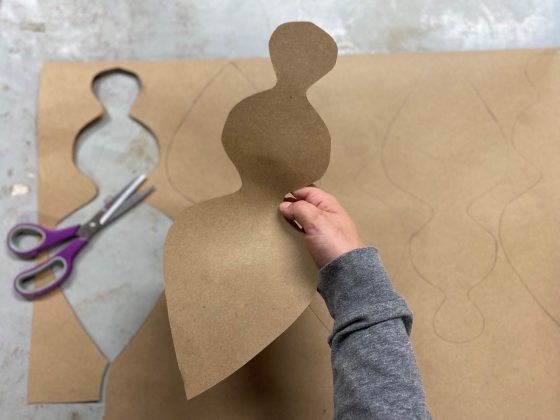 A person cutting out brown paper shapes.