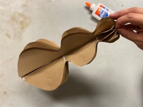 A person holding a brown paper ornament ready to be decorated.