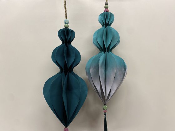 Two paper ornaments spray painted in dark teal and silver.