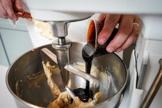 A baker pouring molasses into a mixing bowl.