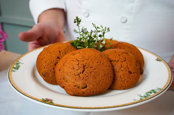 A person showing off a plate of ginger molasses cookies on a white plate.