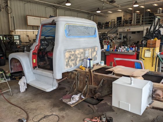 A vintage truck being primed and restored in a mechanic shop. 