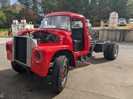 A freshly painted red pick-up truck with no bed or doors. 