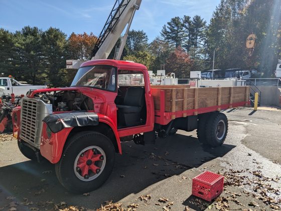 A freshly painted red pick-up truck with a wooden bed and no doors. 